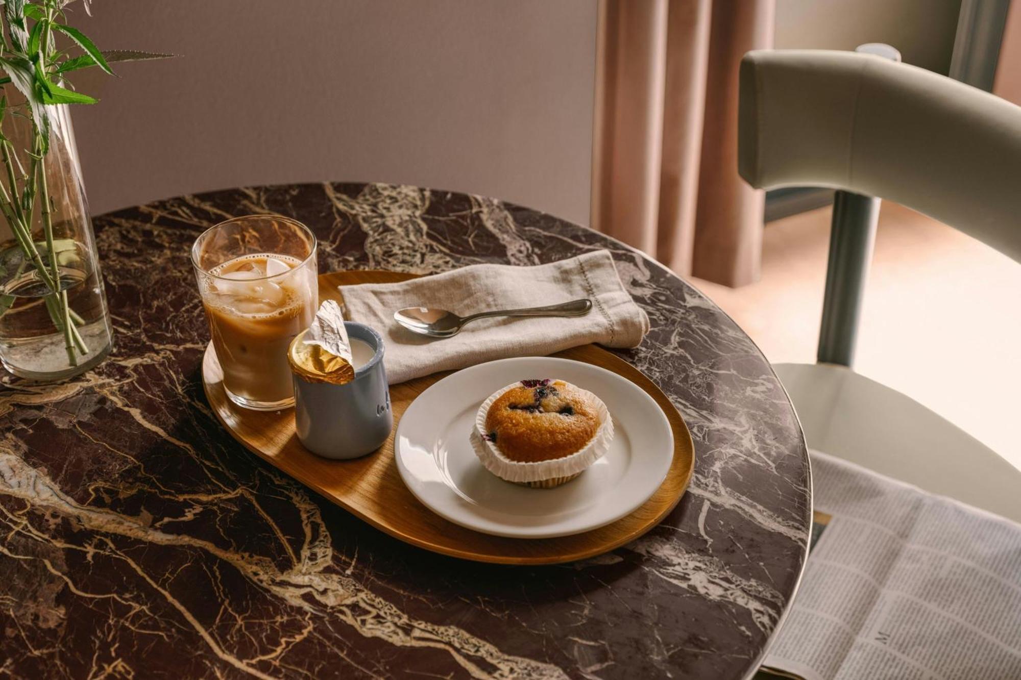 Breakfast tray with iced coffee and a muffin on a marble table in a hotel suite
